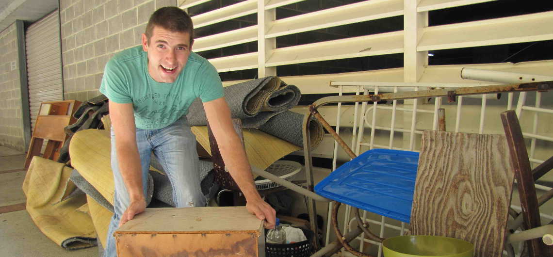 Man double handling rubbish removal waste into a skip bin on the NSW Central Coast